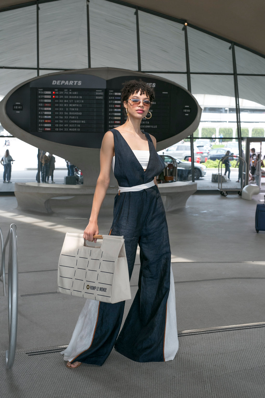 A woman wearing a dress holds a bag in an airport