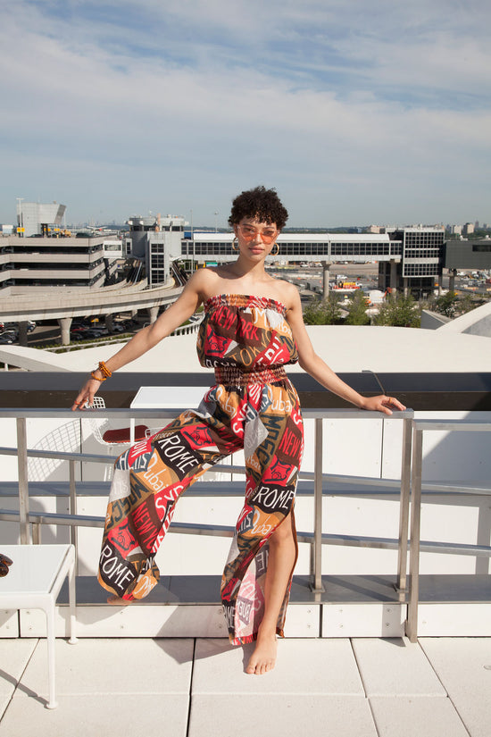 A woman in a romper poses on a balcony