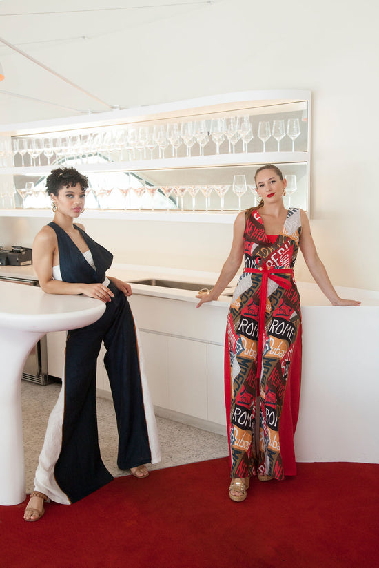 two women wearing rompers stand in a lounge