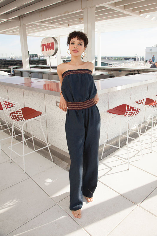 a woman in a romper leans against a bar