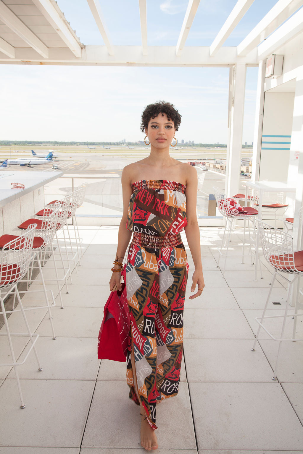 a woman wearing a romper is holding a bag