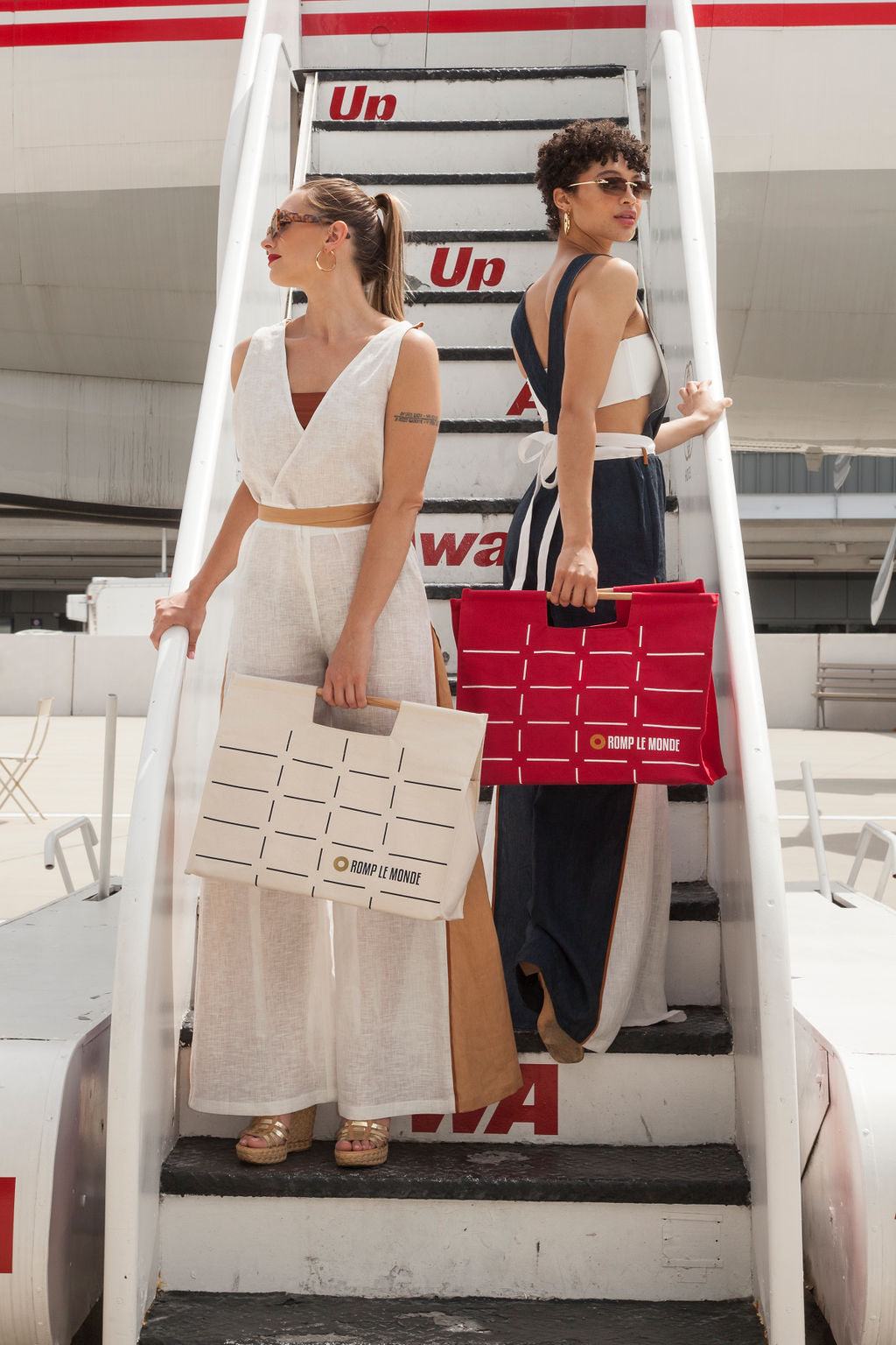 two woman holding bags board an airplane